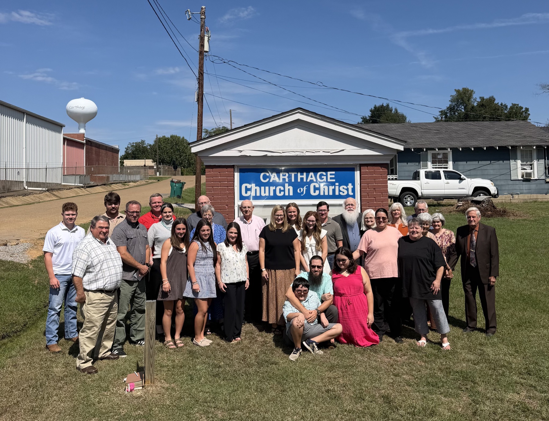 The Carthage Church of Christ congregation gathered outdoors beside the church sign